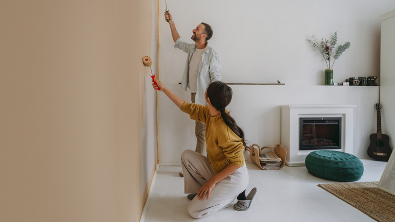 A couple painting the wall of a house