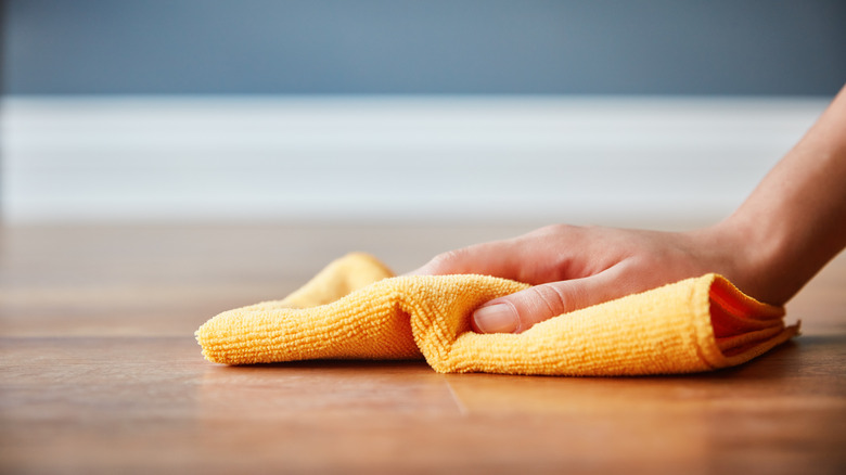 Close-up of a hand cleaning a floor with a cloth