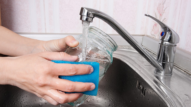 Hands cleaning a jar under a tap
