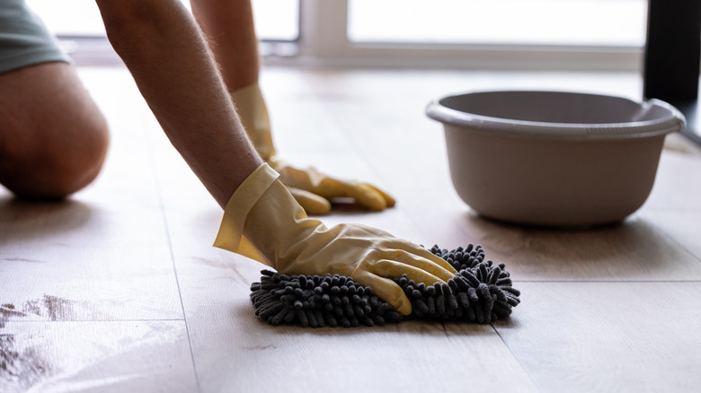A person cleaning the floors of a house with a cloth