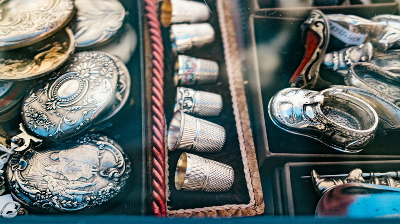 Various sterling silver trinkets with vintage thimbles in the forefront