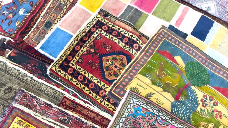 Various vintage rugs of different styles and colors stacked over each other.