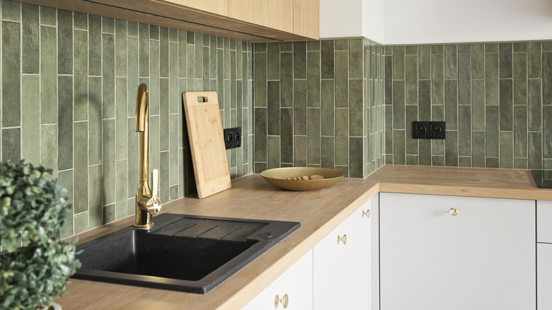A kitchen with a sage green, vertical subway tile backsplash.