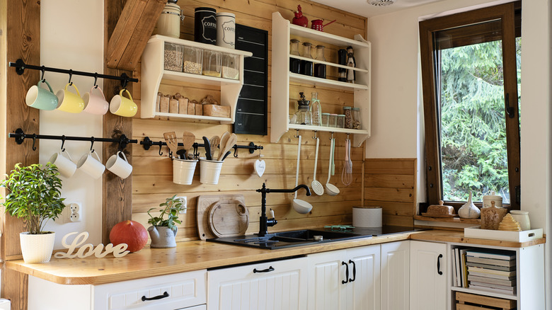 A modern farmhouse kitchen with white cabinets, matte black hardware, and exposed wood.