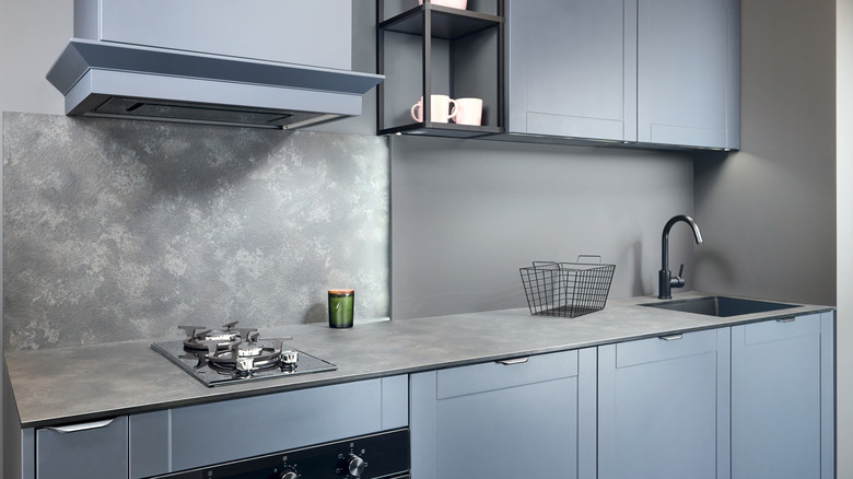 A modern gray and blue contemporary kitchen with laminate countertops and backsplash.