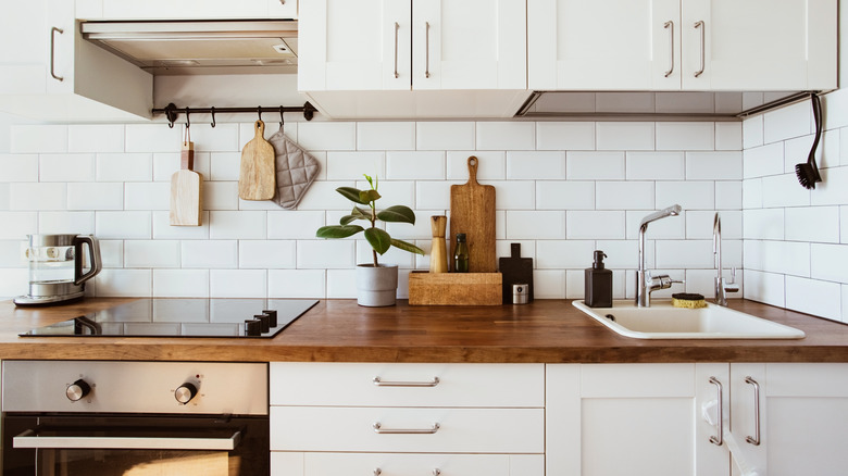 A white kitchen with a darker, warm butcher block countertop.