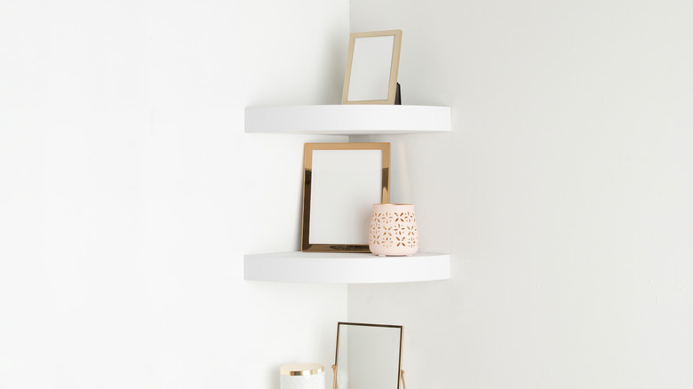 Small white shelves in corners with picture frames and other decorative items