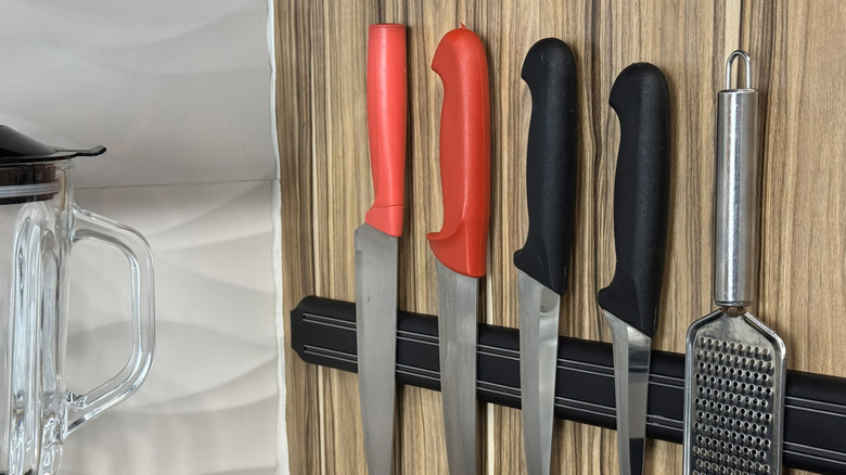 Kitchen knives and a grater stored on a magnetic rack