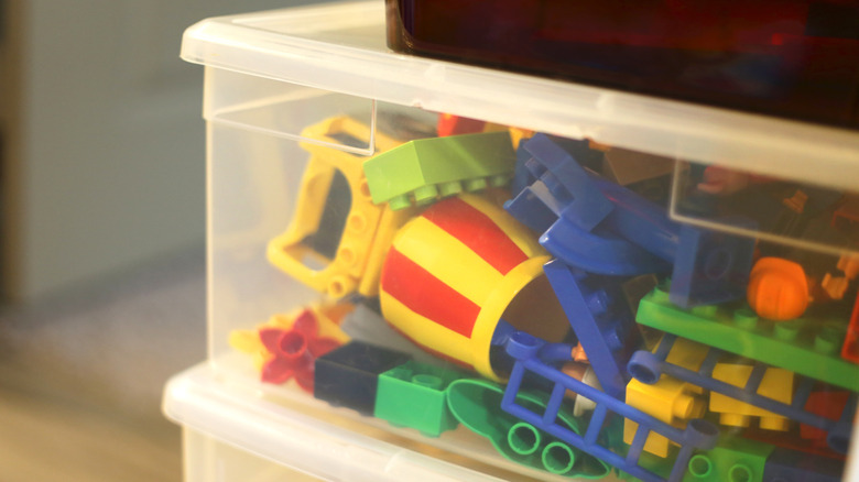 Two clear plastic boxes stacked on top of each other, filled with toys