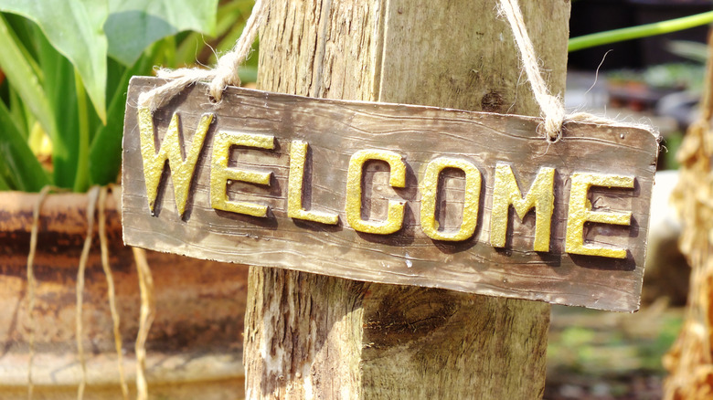 Wooden welcome sign hanging on post in garden