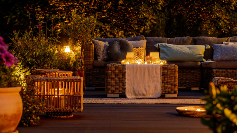 A patio area with several candles and lanterns illuminating the space