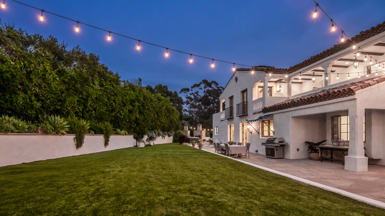 Large string lights spanning across a grassy backyard area connecting to the house