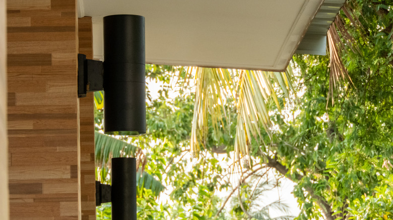 Two modern, slim, black wall sconces installed on the side of a home
