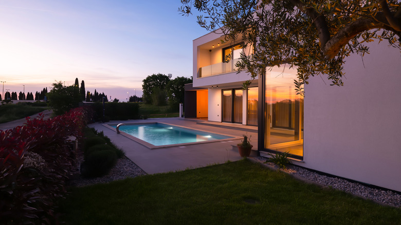 Dimly lit backyard with a pool and patio