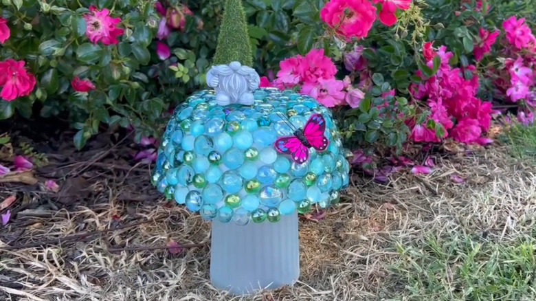 Mushroom made from a bowl covered in gems displayed in a garden