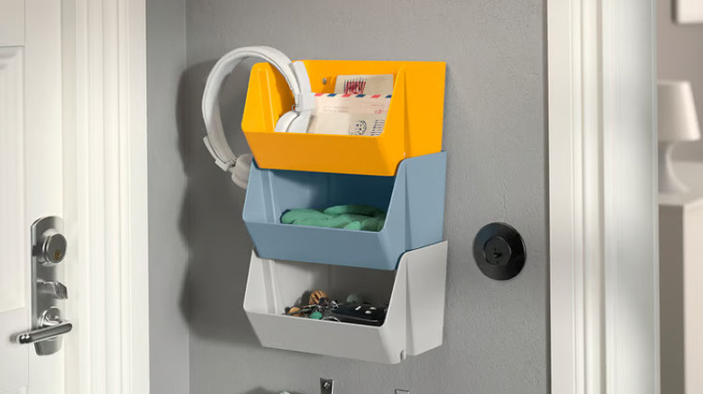 Stacked IKEA plastic organizers in various colors on bedroom wall filled with personal clutter