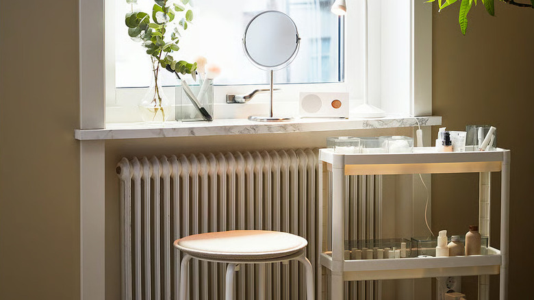 White rolling cart filled with feminine clutter beside open window and stylish stool