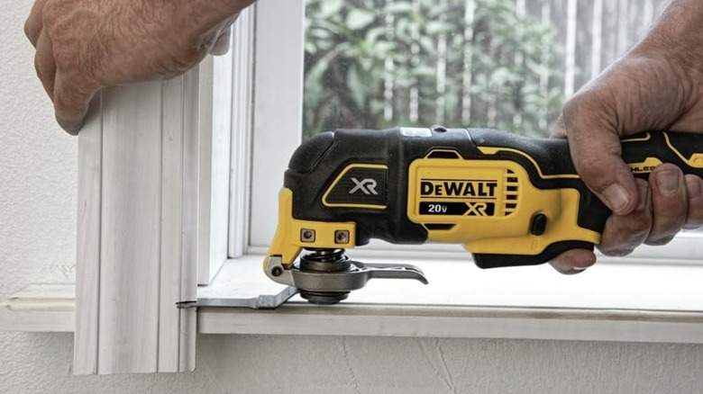Man using DeWalt MAX XR Oscillating Tool to cut window frame