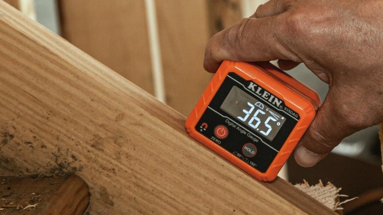 Man using Klein Tools 935DAG Electronic Level on angled piece of wood