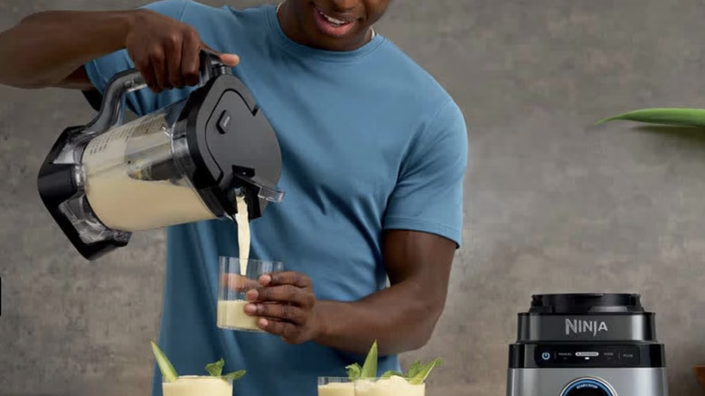 A man pours blended drinks into individual glasses.