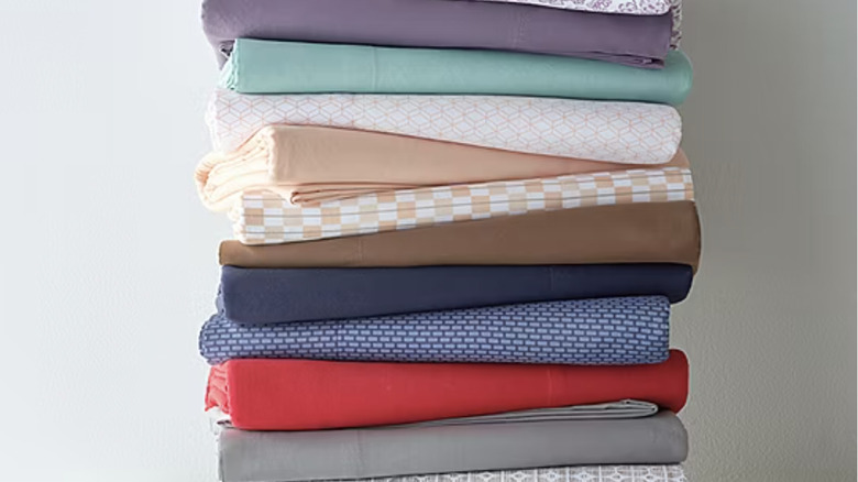 A stack of folded microfiber sheets in a variety of colors and patterns.