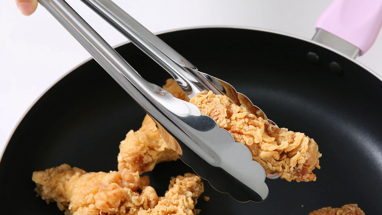 Closeup of Walmart's cooking tongs holding a chicken nugget