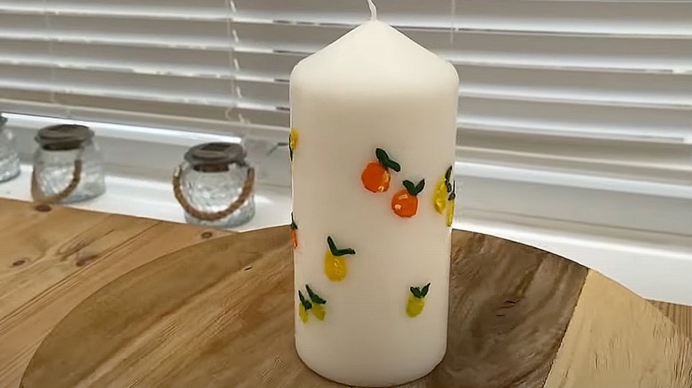 White pillar candle painted with little citrus fruits
