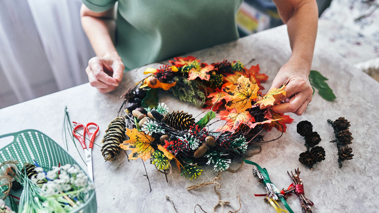 A woman puts together a foraged autumn wreath