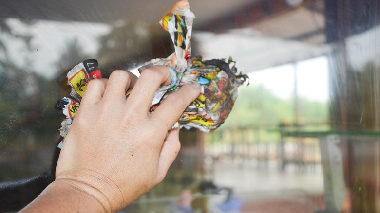 hand wiping glass with newspaper