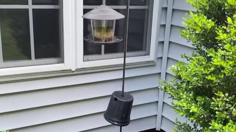 A planter upside down on a bird feeder to deter squirrels