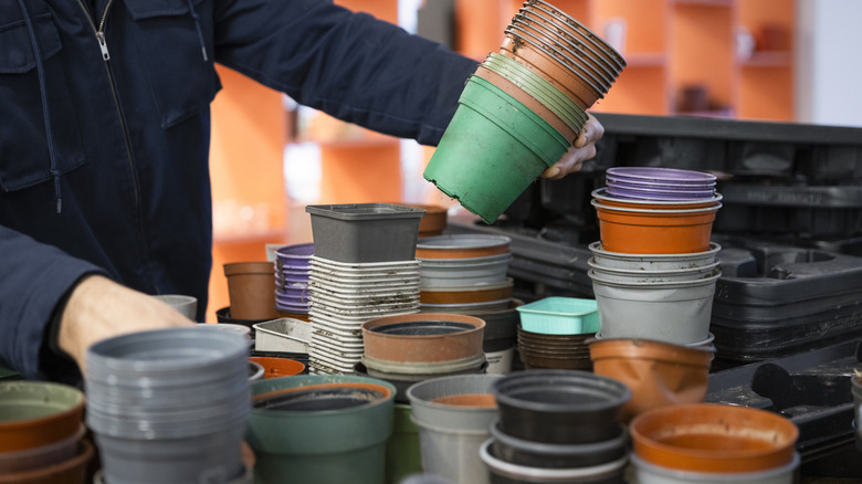 A person holds a stack of plastic nursery pots and examines them.