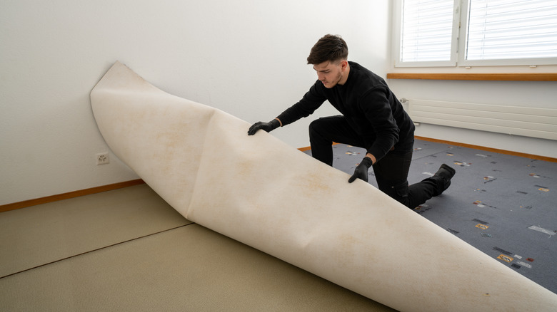 Man pulling up old carpet