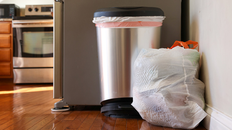 A full garbage bag sitting on the floor in a kitchen