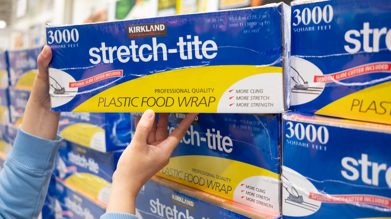 Someone removing Kirkland brand plastic wrap from the shelf.