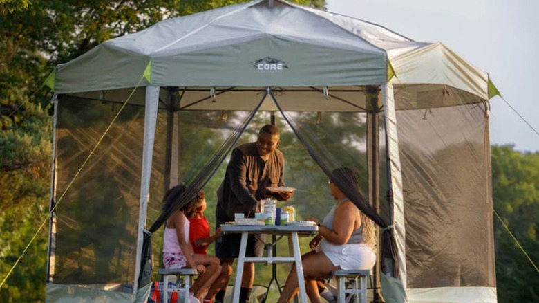 Family sitting around a table inside the CORE Center Push Mesh Screenhouse
