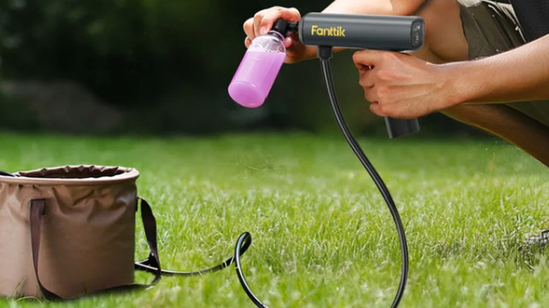 Man using the Fanttik K100 Flip Foldable Pressure Washer outside with green grass in the background