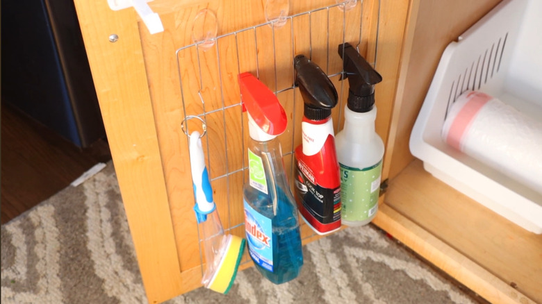 Cleaning supplies hanging from cooling rack slats.