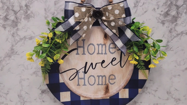 Charger plate painted with "Home Sweet Home" and accented with ribbon and silk flowers