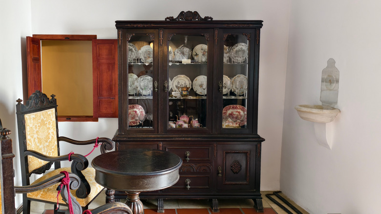 Wood China cabinet displaying porcelain dishes
