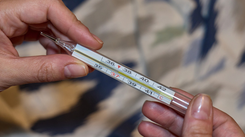 Hands holding a mercury thermometer