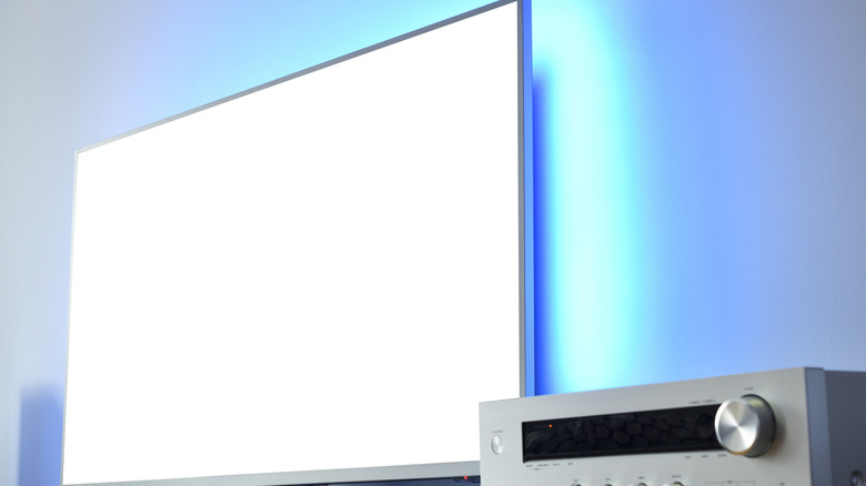 A large backlit TV with an audio receiver nearby