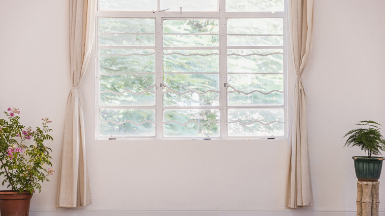 Skinny cream curtains tied back around a window