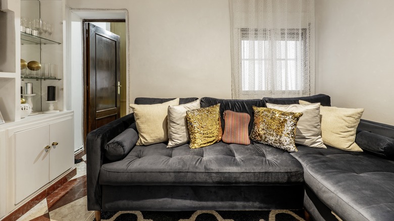 A large black velvet sofa in a small living room