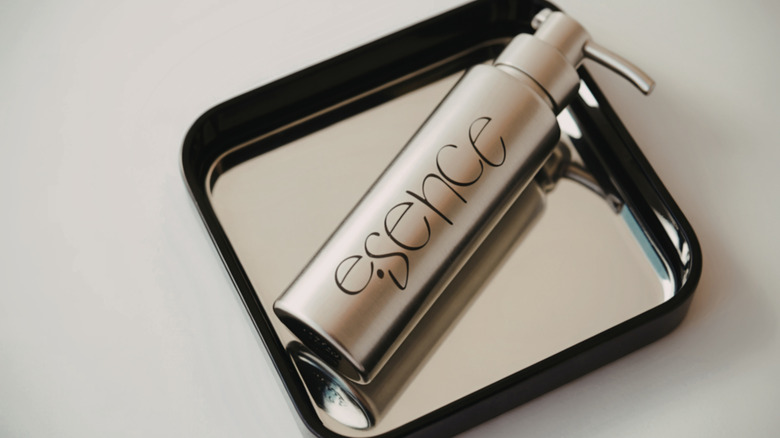 A pump bottle of lotion on a tiny square mirrored tray