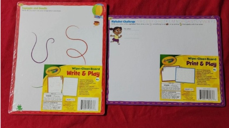 Two Crayola Wipe-Clean boards on a red surface