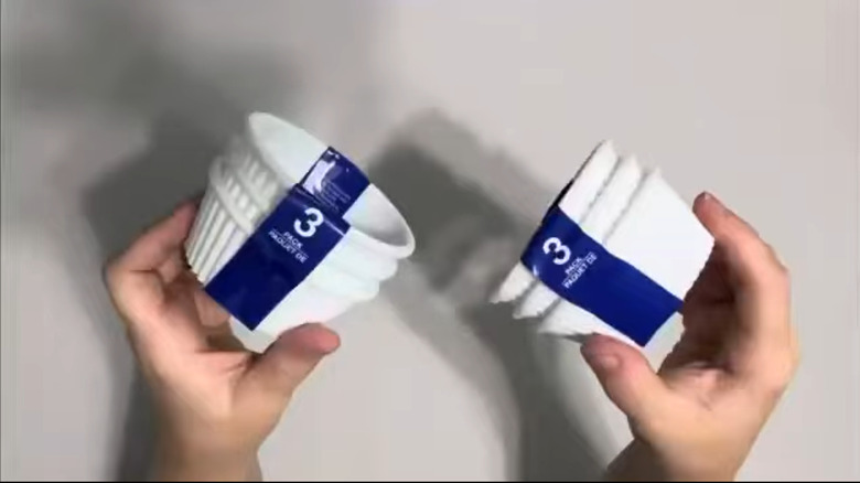 Hands holding two three-sets of white ramekins
