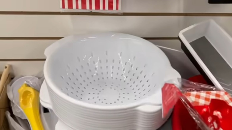Stack of white colanders on shelf
