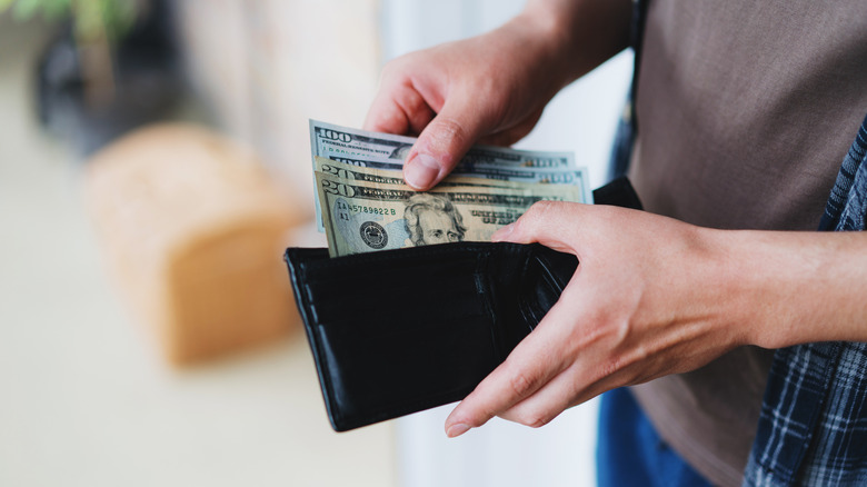 Hands counting notes out of a wallet