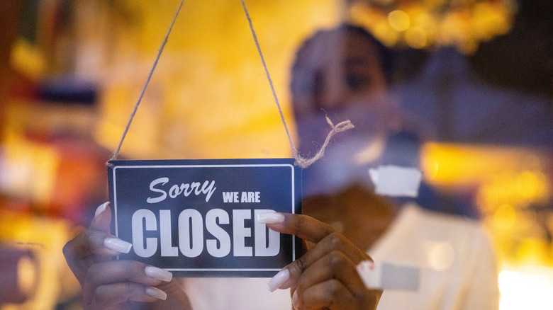Woman putting a closed sign on a storefront