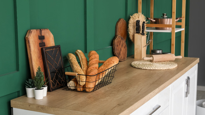 A kitchen counter with wooden cutting boards and a basket of bread